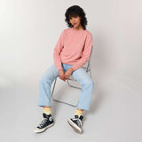Unisex Crew Neck Sweatshirt in soft pink, styled with light blue jeans and black high-top sneakers, ideal for retail, events, and workwear branding.