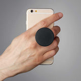 Black Dot Phone Holder used as grip on smartphone. Functional tech accessory for branding and mobile phone handling.